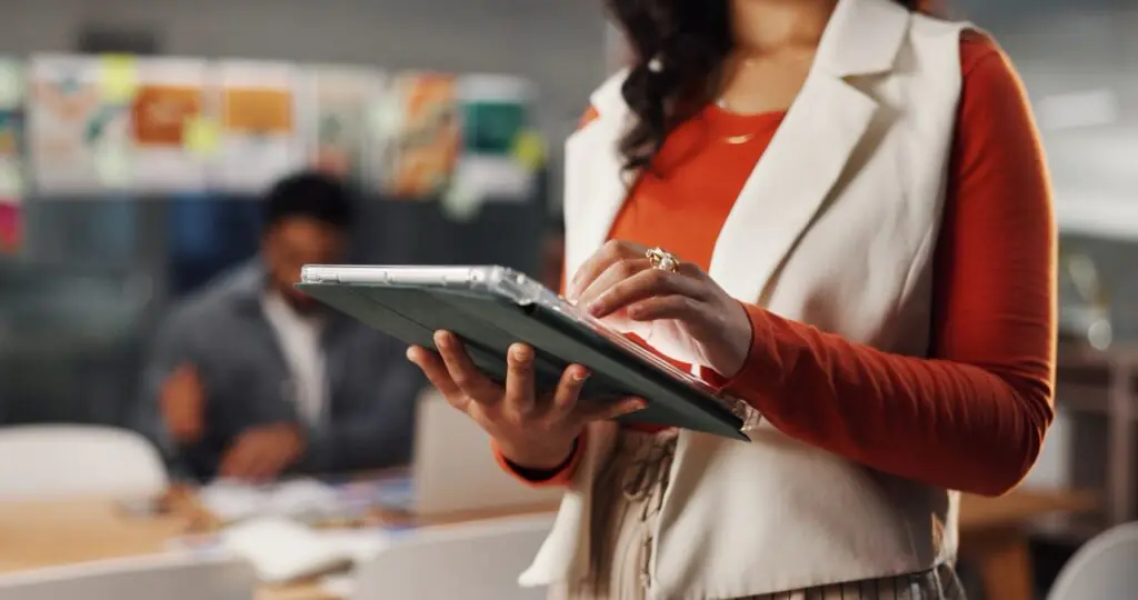 Staff member using a tablet during IDD software onboarding with a colleague working in the background