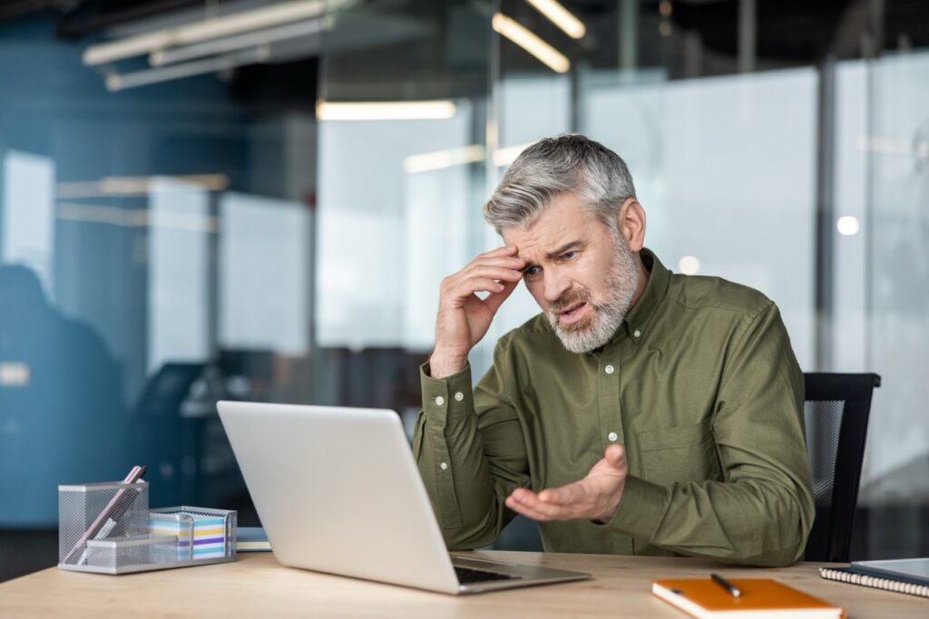 Frustrated agency leader dealing with IDD software mistakes on his laptop